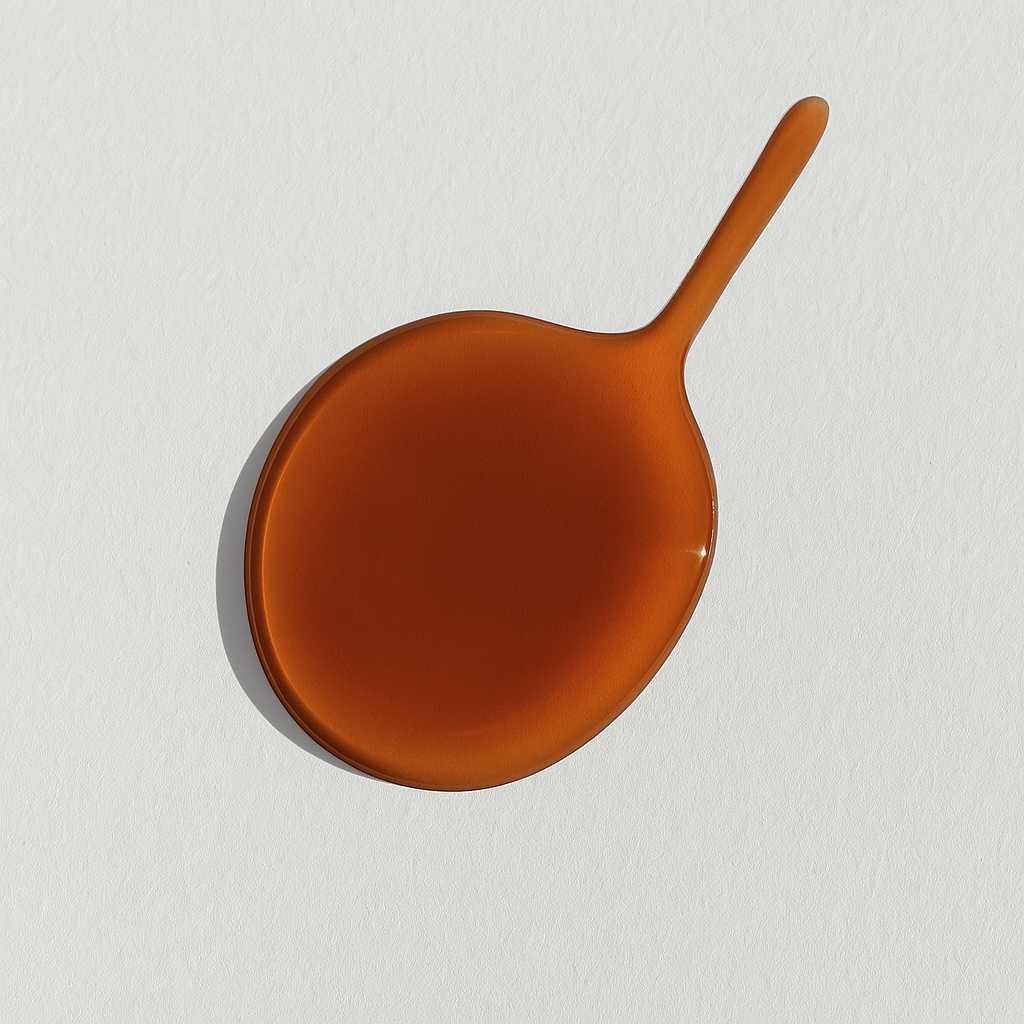 Amber droplet of Desert Fleur perfume oil on a white surface, captured in soft natural light with a smooth, reflective finish.